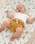 Baby lying on cot fitted sheet in Run Wild design, soft cotton with playful jungle animal prints for a cosy, breathable sleep