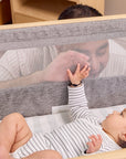 Dad looking at baby through mesh side of CoZee Air Bedside Crib in Oak and Charcoal – safe, visible co-sleeping setup