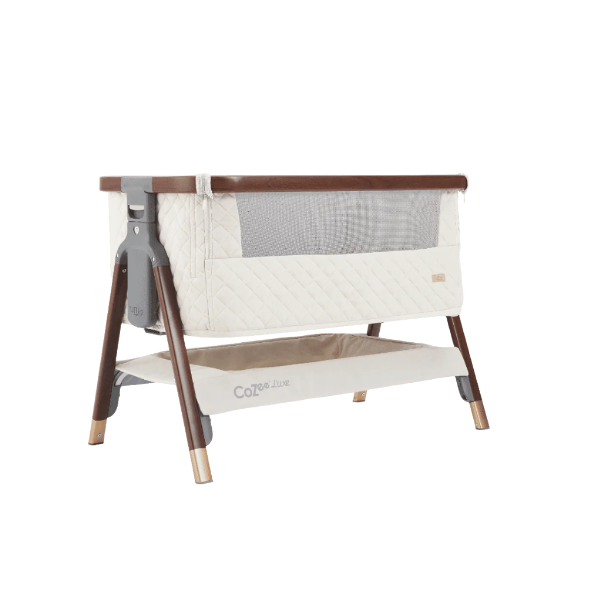 Angled cutout view of the CoZee Luxe crib in walnut and cream finish showing mesh window, quilted sides, and storage shelf
