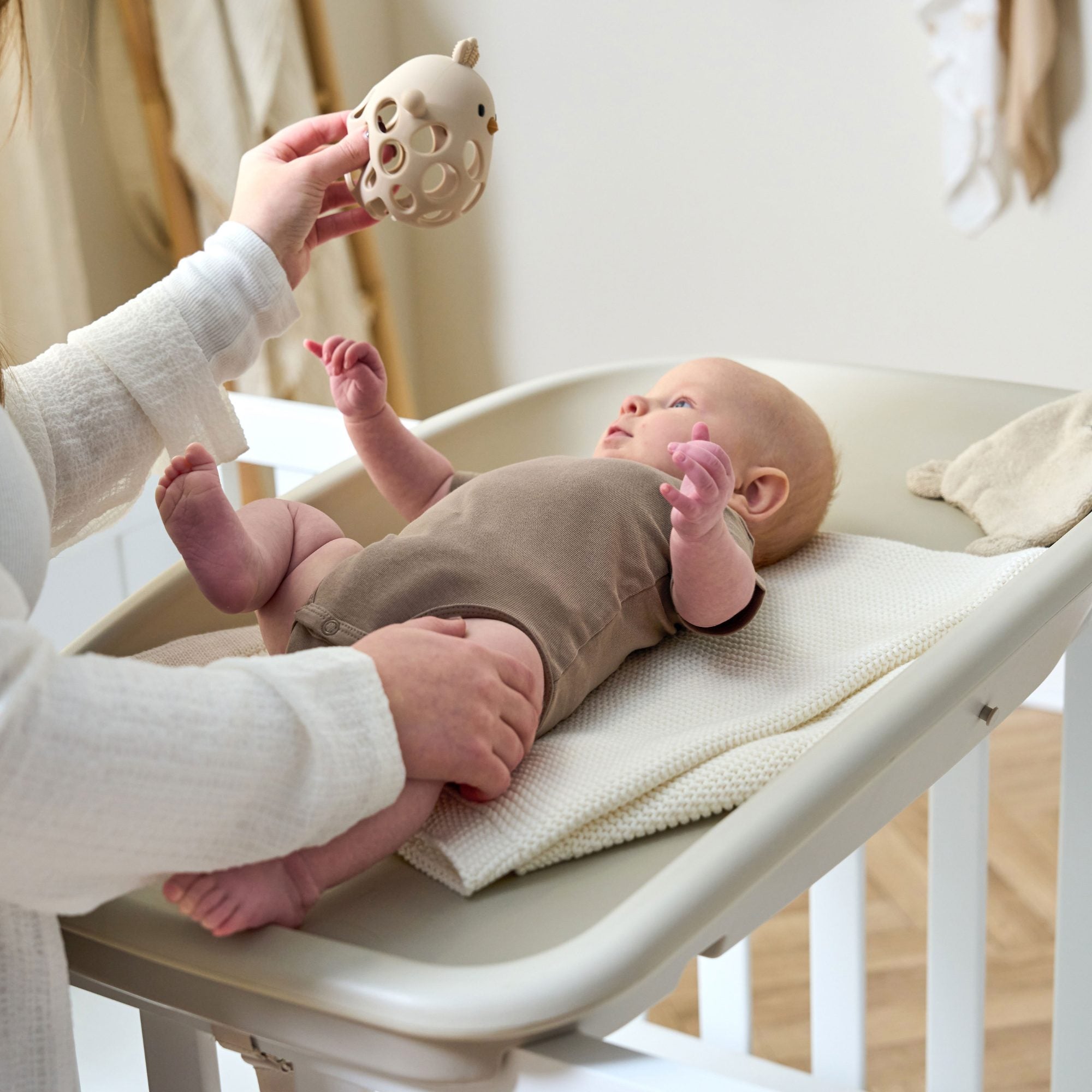 Baby lying comfortably on the Cushi changing mat in mushroom, highlighting soft curved design and secure fit