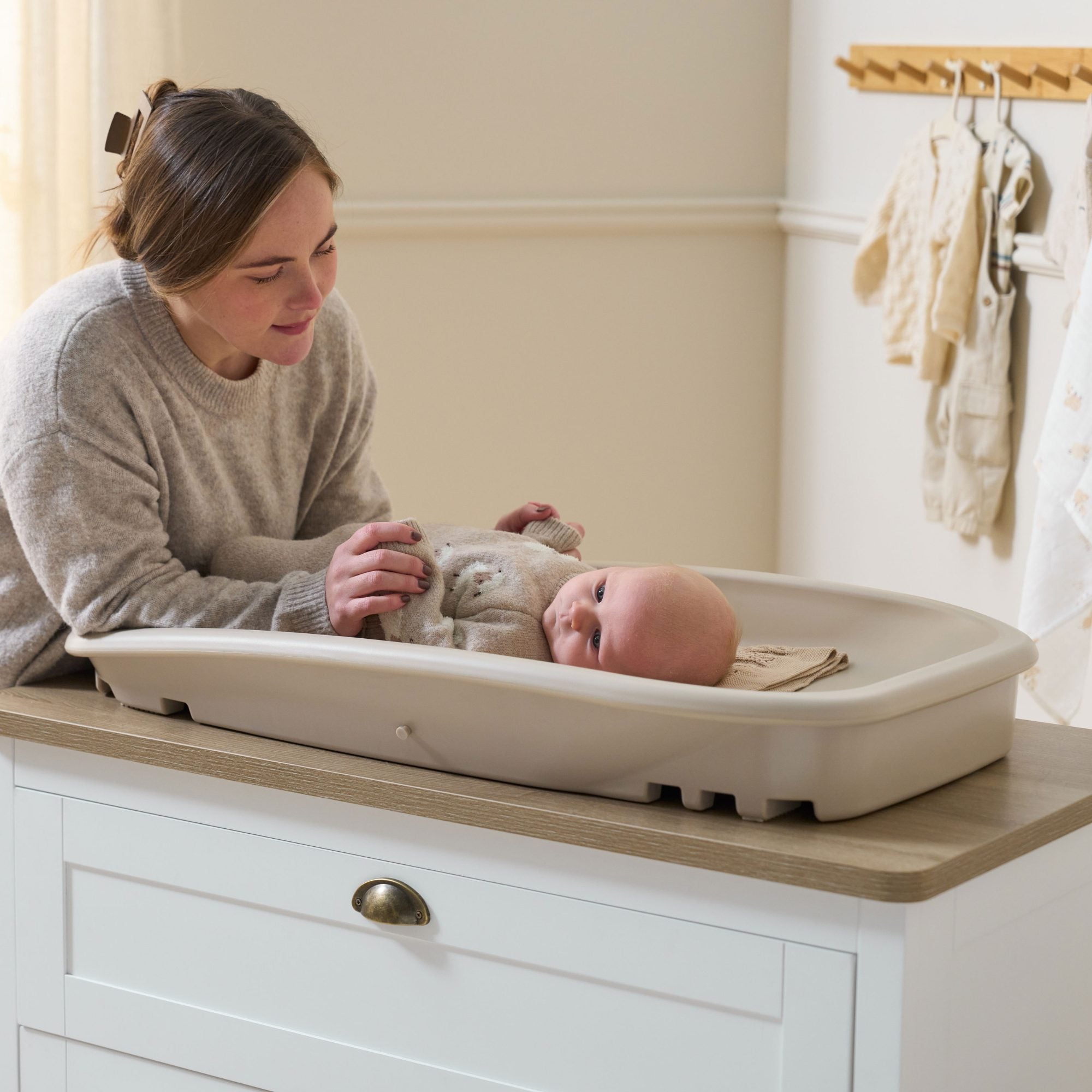 Parent interacting with baby on the Cushi changing mat in mushroom, shown in use on chest changer for everyday convenience