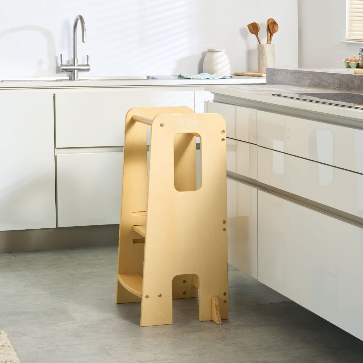 Lifestyle kitchen view of the Helping Hands Montessori toddler learning tower in natural finish, blending seamlessly into a modern home