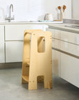 Lifestyle kitchen view of the Helping Hands Montessori toddler learning tower in natural finish, blending seamlessly into a modern home
