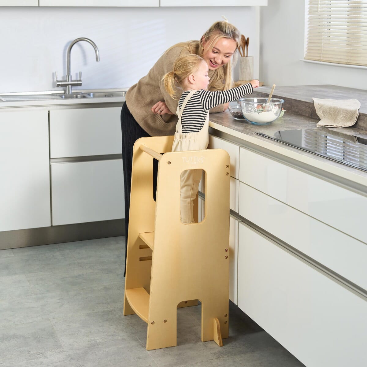 Mother and toddler prepare food together using the Helping Hands Montessori learning tower in natural wood, supporting safe interactive kitchen play