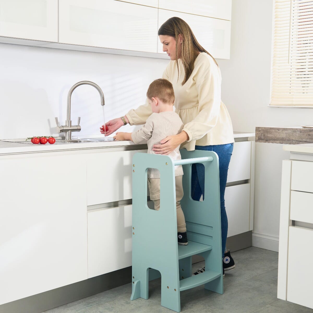 Mum supports toddler preparing food at the counter with the Helping Hands Montessori learning tower in ocean stone, promoting safe independence