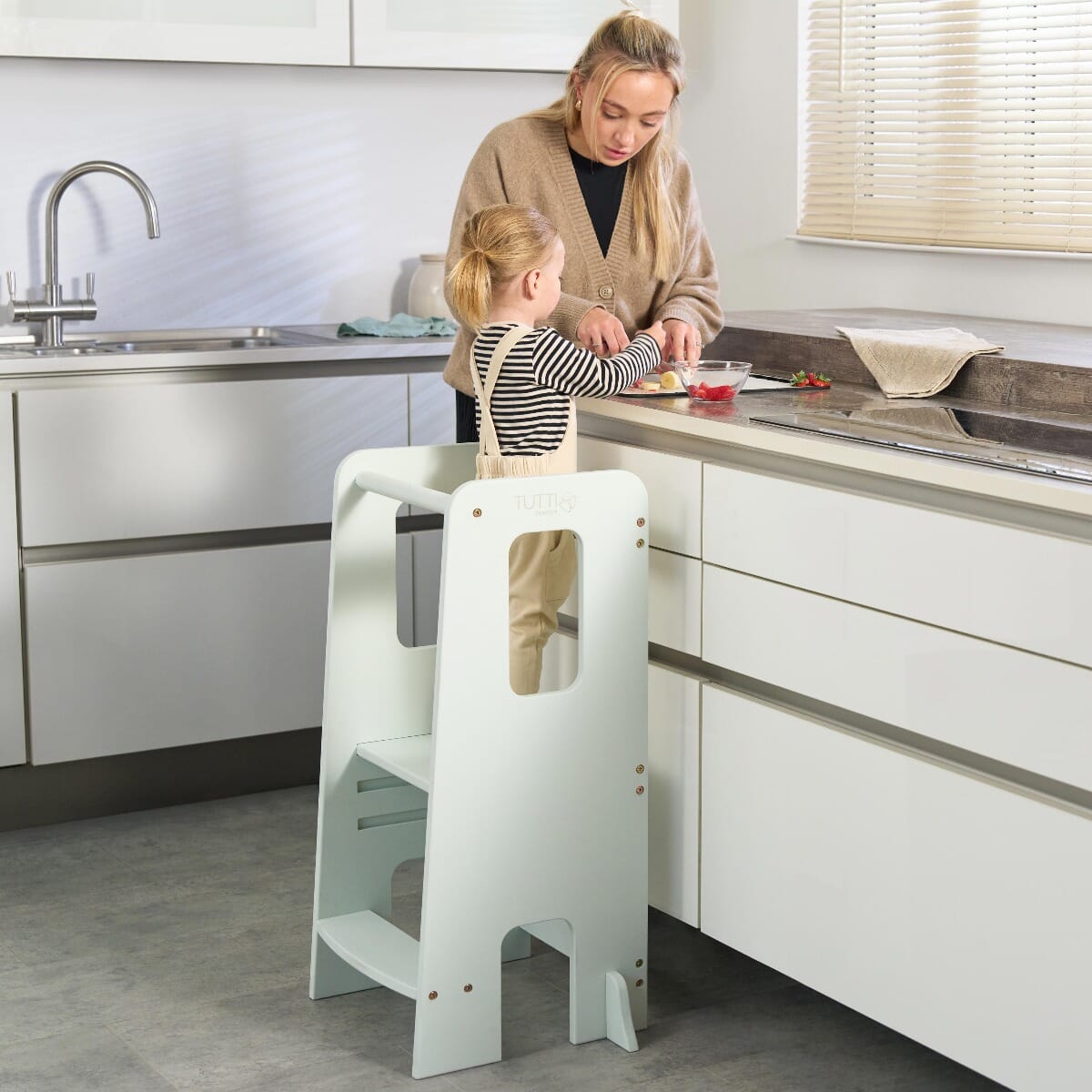 Mum and toddler cooking together at the kitchen counter using the Helping Hands Montessori Learning Tower in sea mist for safe access