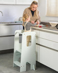 Mum and toddler cooking together at the kitchen counter using the Helping Hands Montessori Learning Tower in sea mist for safe access