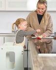 Toddler preparing food with mum using the Helping Hands Montessori Learning Tower in sea mist, fostering independence and family interaction