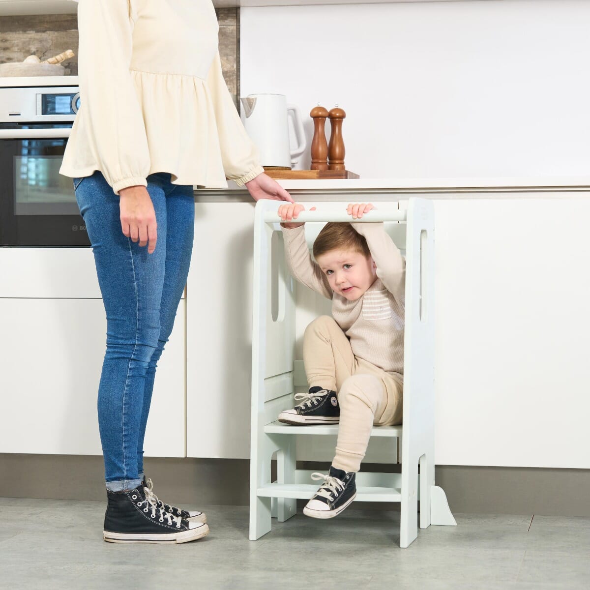 Young boy climbing through the Helping Hands Montessori Toddler Learning Tower in sea mist, showing playful and versatile use at home
