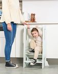 Young boy climbing through the Helping Hands Montessori Toddler Learning Tower in sea mist, showing playful and versatile use at home