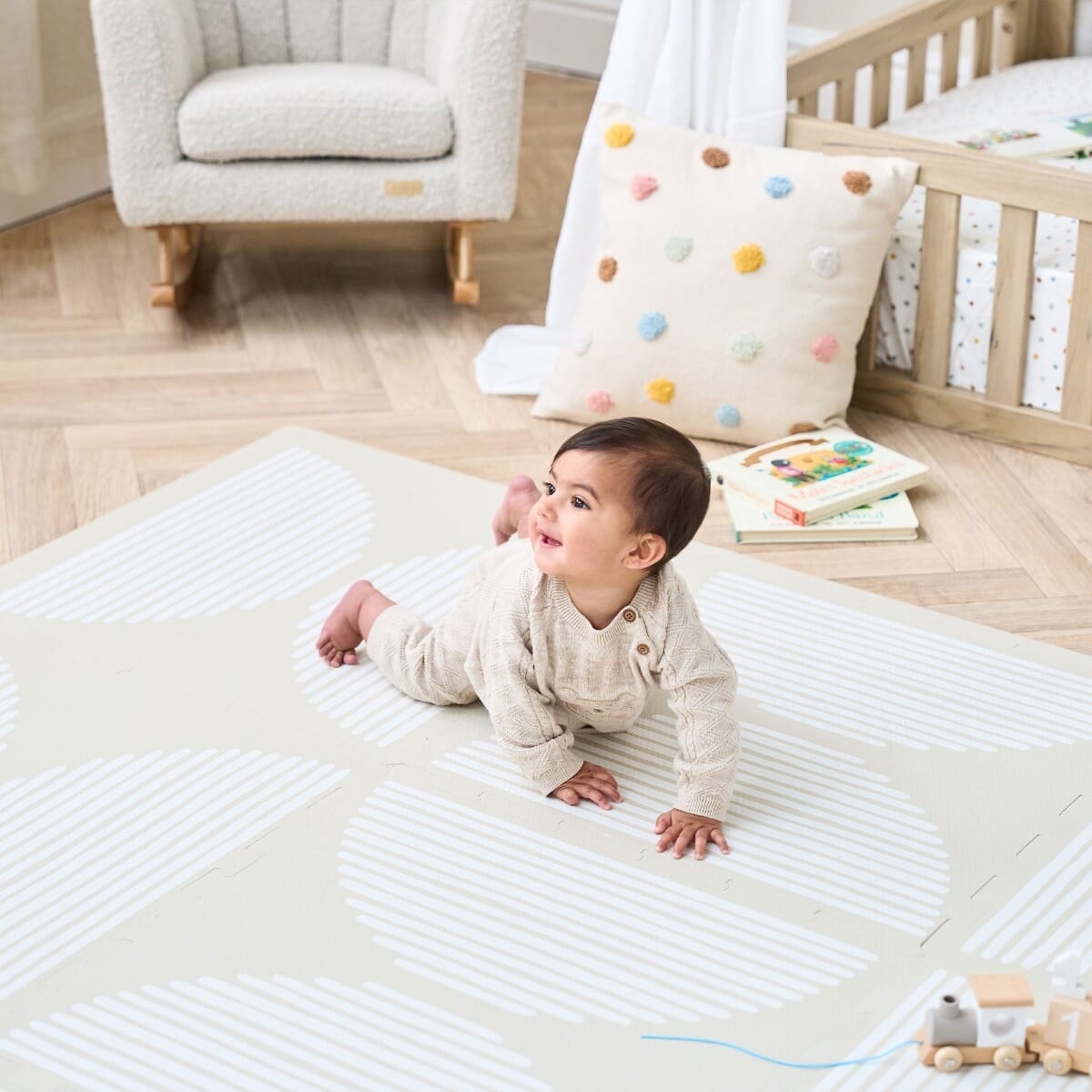 baby smiling and crawling on the infinity baby playmat in orbital oatmeal