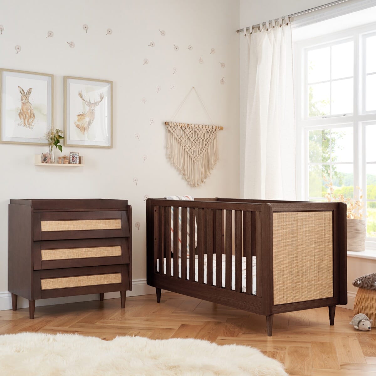 Japandi 2-piece nursery furniture set in warm walnut shown in a styled room, showcasing the cot bed and chest changer with warm tones, rattan texture, and Scandi-inspired details.