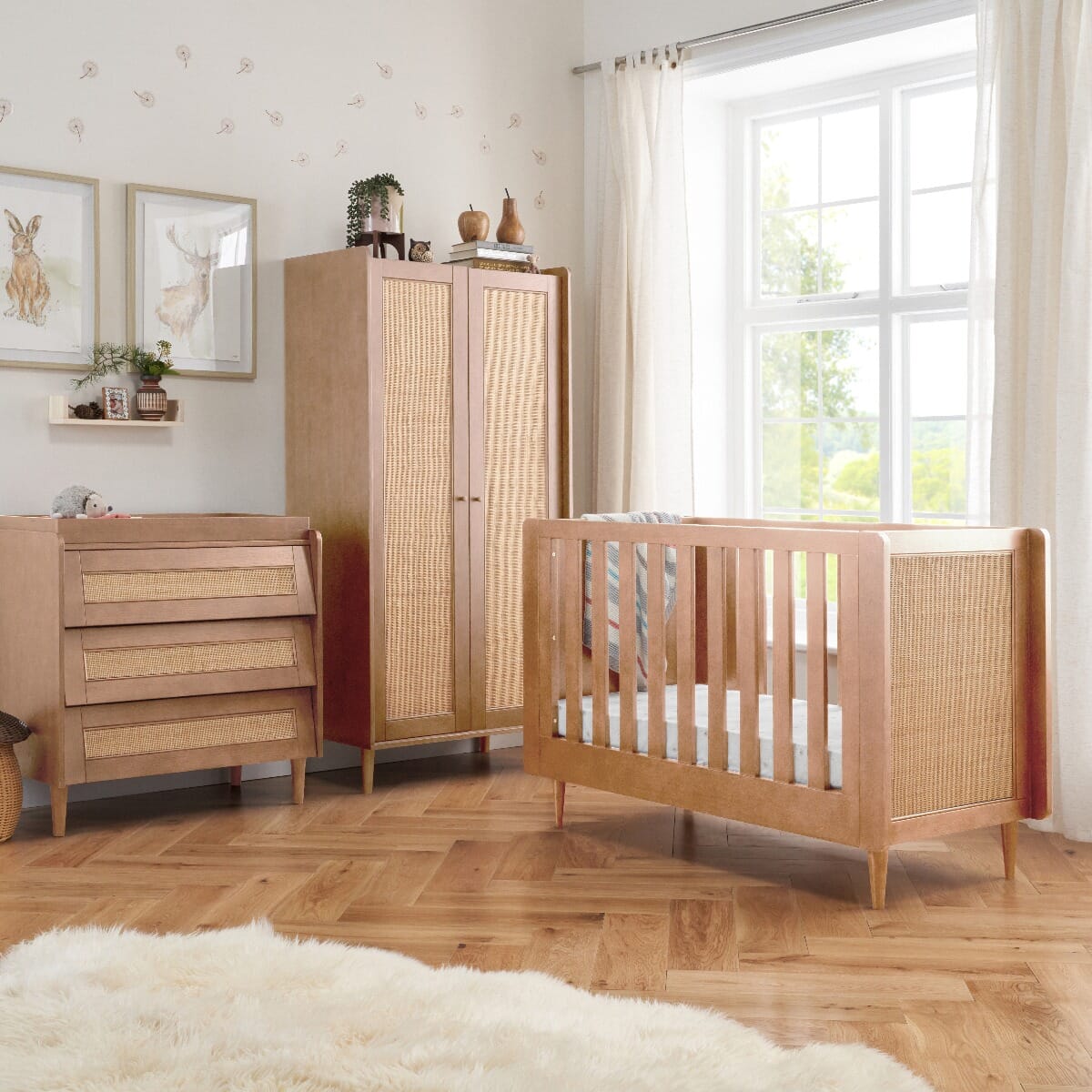 Japandi nursery furniture set in light oak displayed in a styled room, featuring a cot bed, chest changer, and wardrobe with rattan details and a calming, natural aesthetic.
