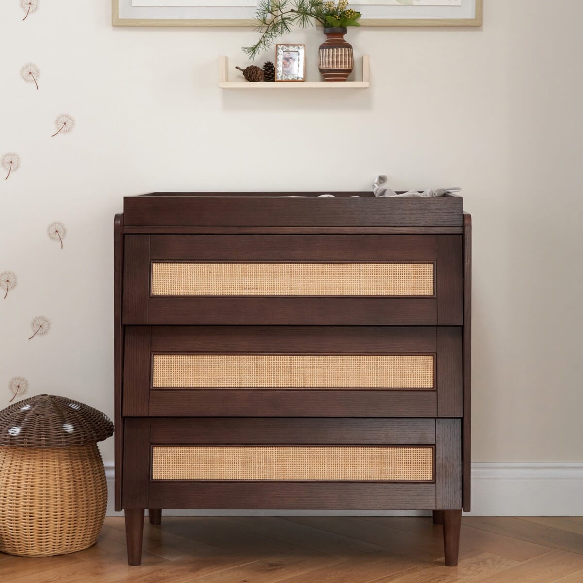 Japandi chest changer in warm walnut with three spacious drawers and rattan detailing, blending natural materials with a contemporary silhouette for stylish storage.