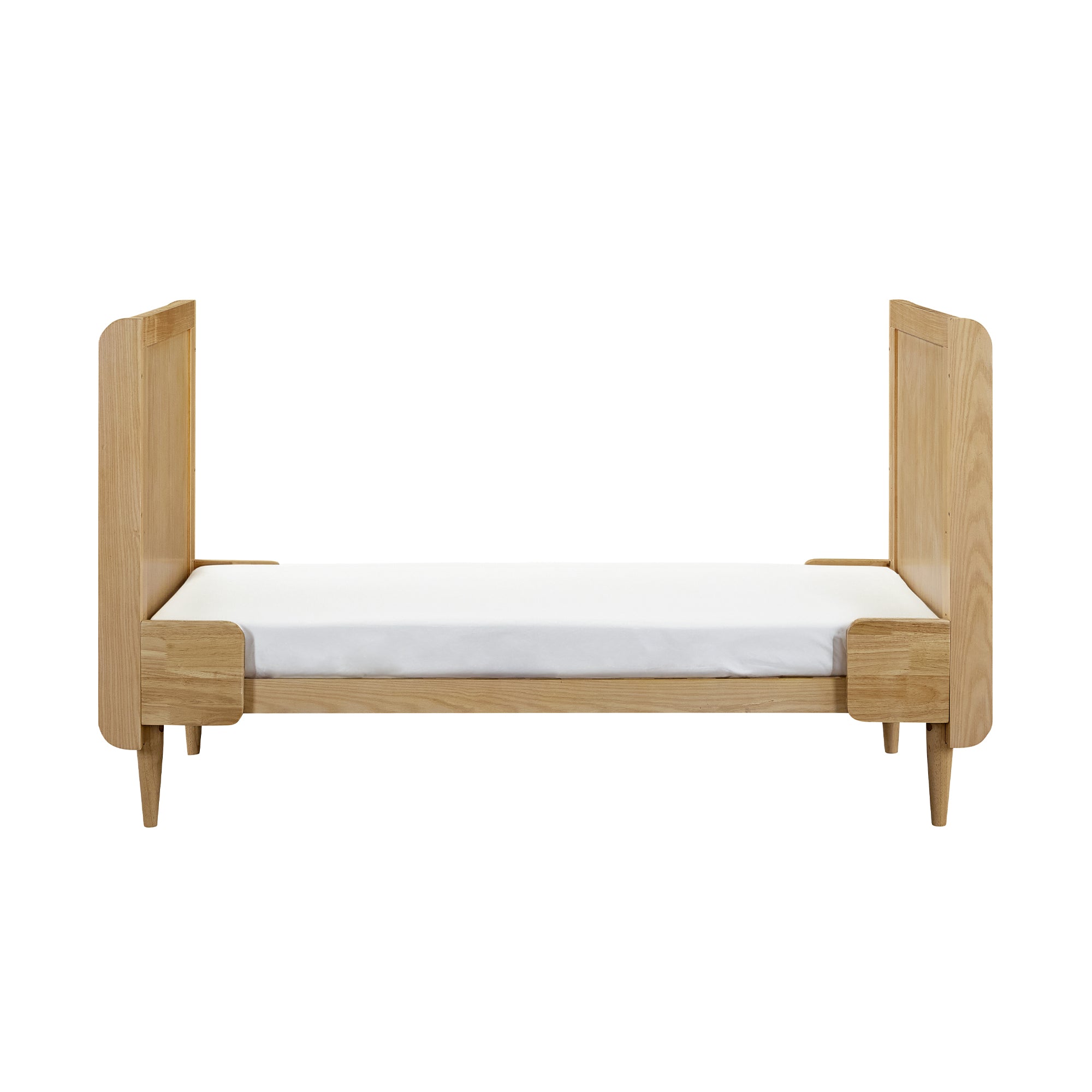 Japandi cot bed in light oak converted to toddler bed mode, featuring a low profile and extended head and footboards for safety and comfort.