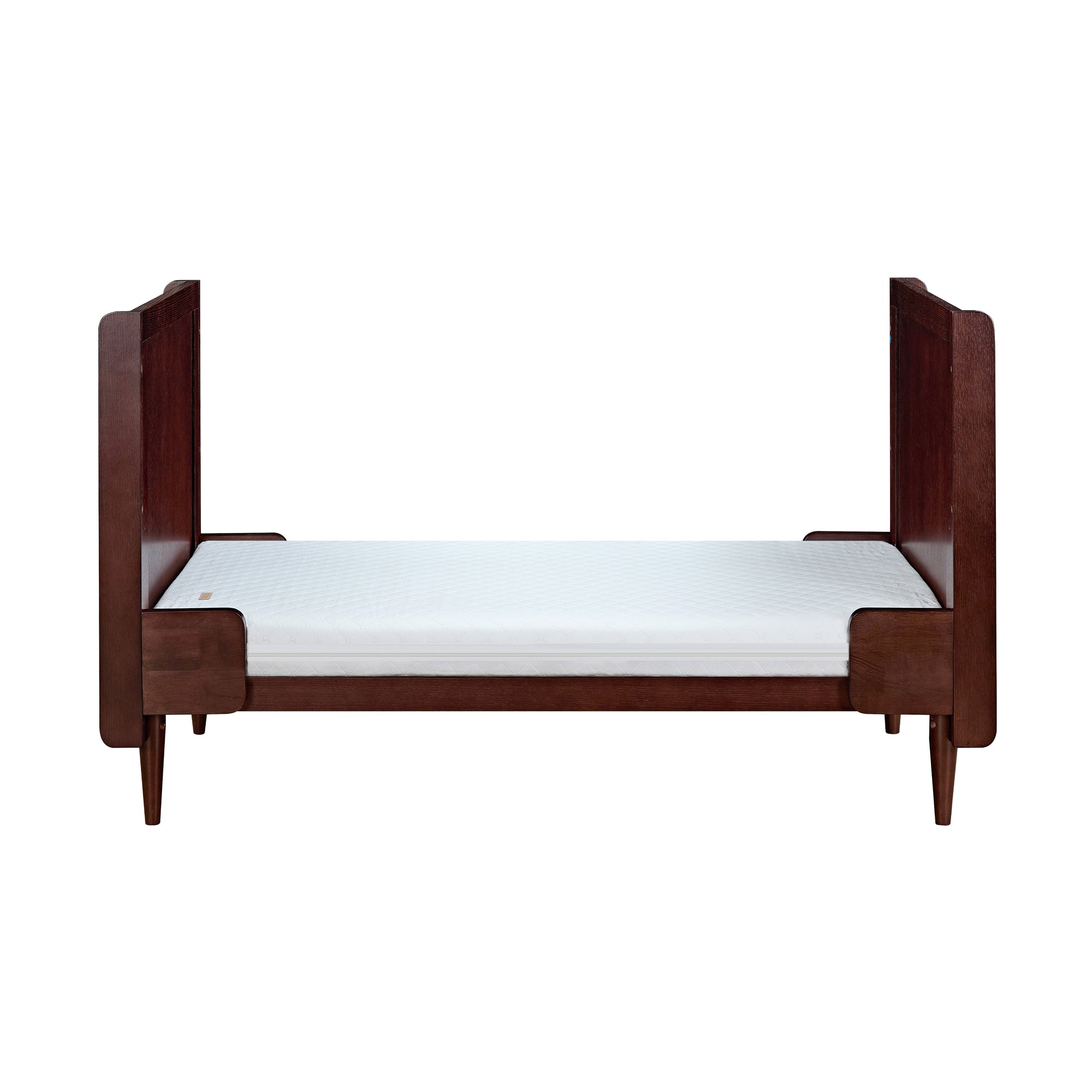 Japandi cot bed in warm walnut converted to toddler bed mode, designed with extended head and footboards for safety and transitional comfort.