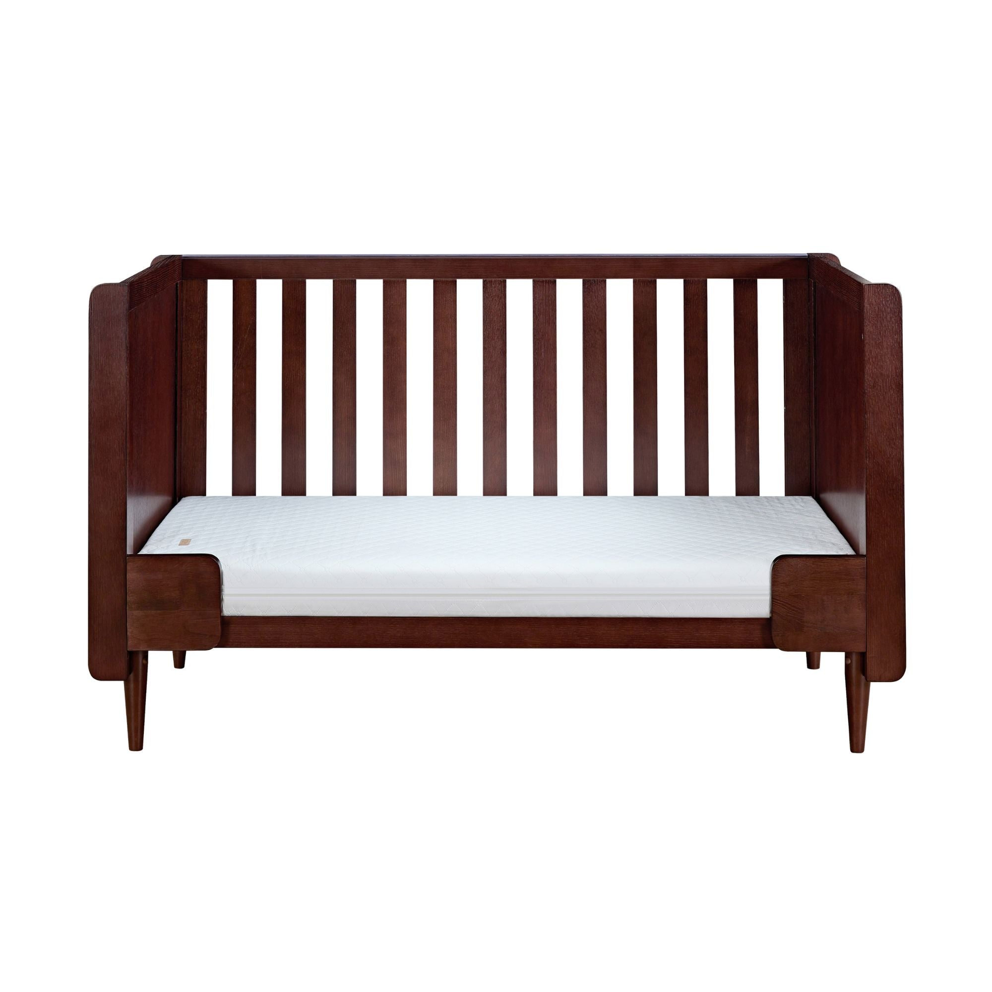 Japandi cot bed in warm walnut shown in sofa bed mode, featuring open side access and supportive side panels for relaxed seating.