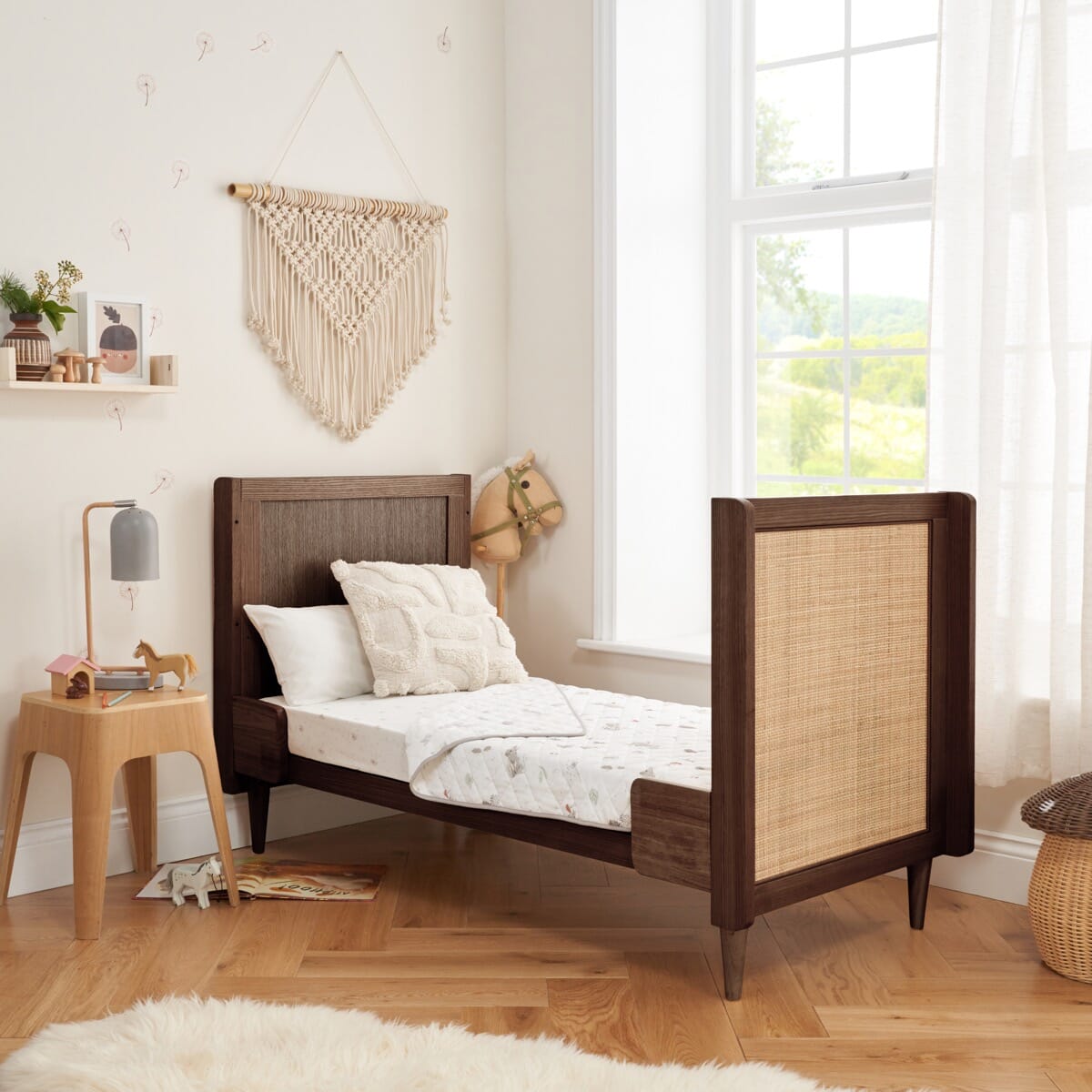 Japandi cot bed in warm walnut shown in toddler bed mode with mattress lowered and rails removed, designed to support independence and comfort for toddlers.