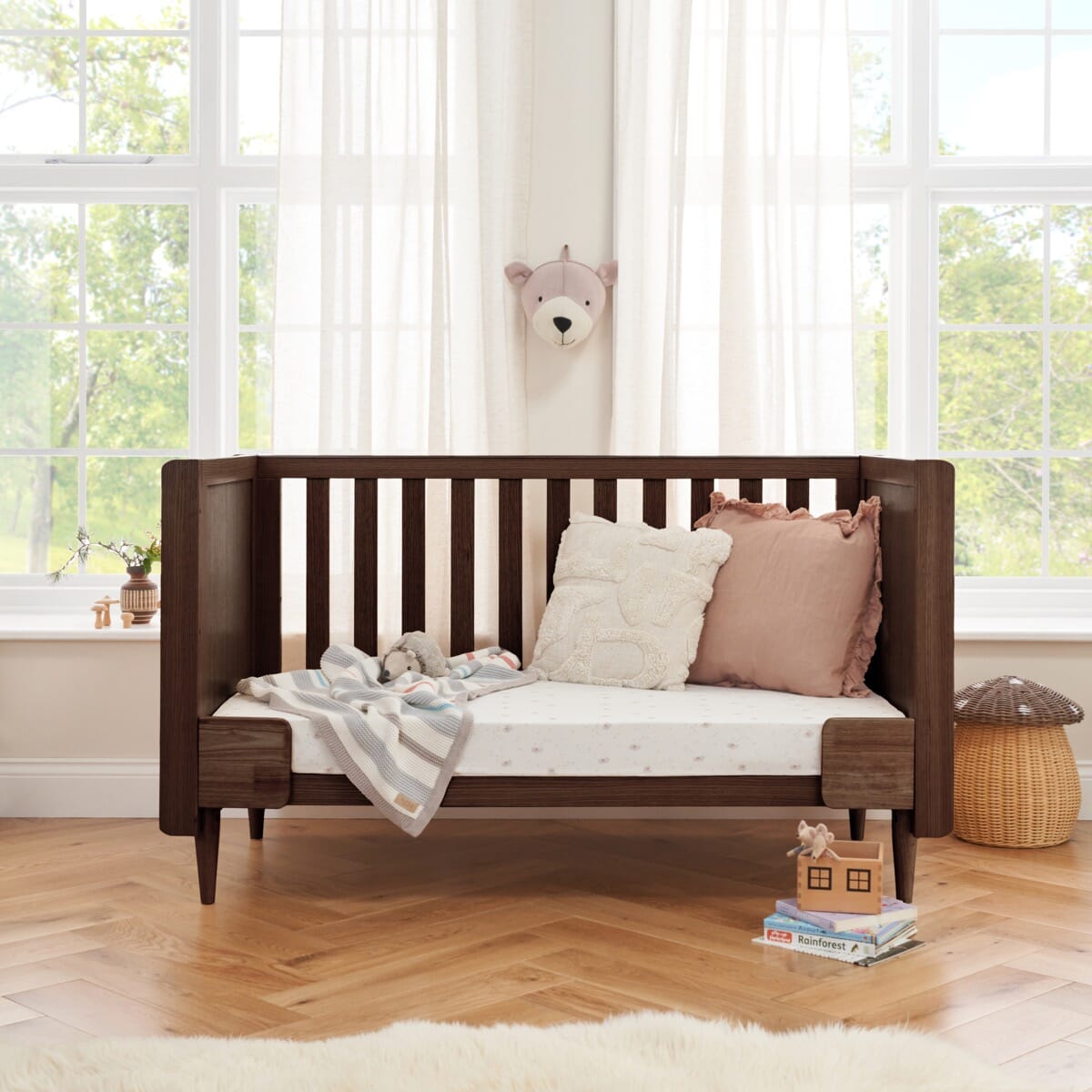 Japandi cot bed in warm walnut converted to sofa bed mode with side rails removed, offering a cosy lounging space