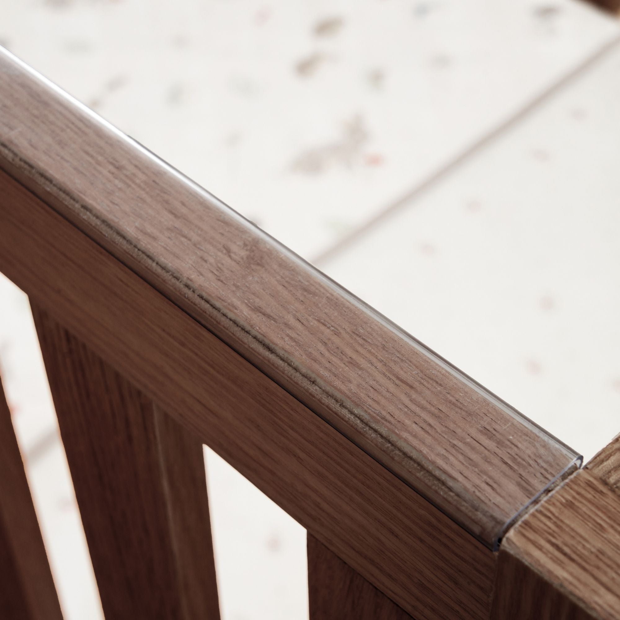 Japandi cot bed in warm walnut close-up of the protective teething rail, made from clear, chew-safe material to protect delicate gums and the wood finish.