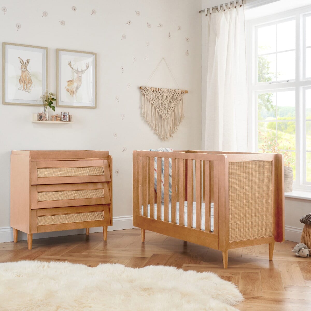 Styled nursery featuring the Japandi mini cot bed and chest changer in light oak with natural cane accents, arranged in a serene, boho-inspired space with dandelion decals.