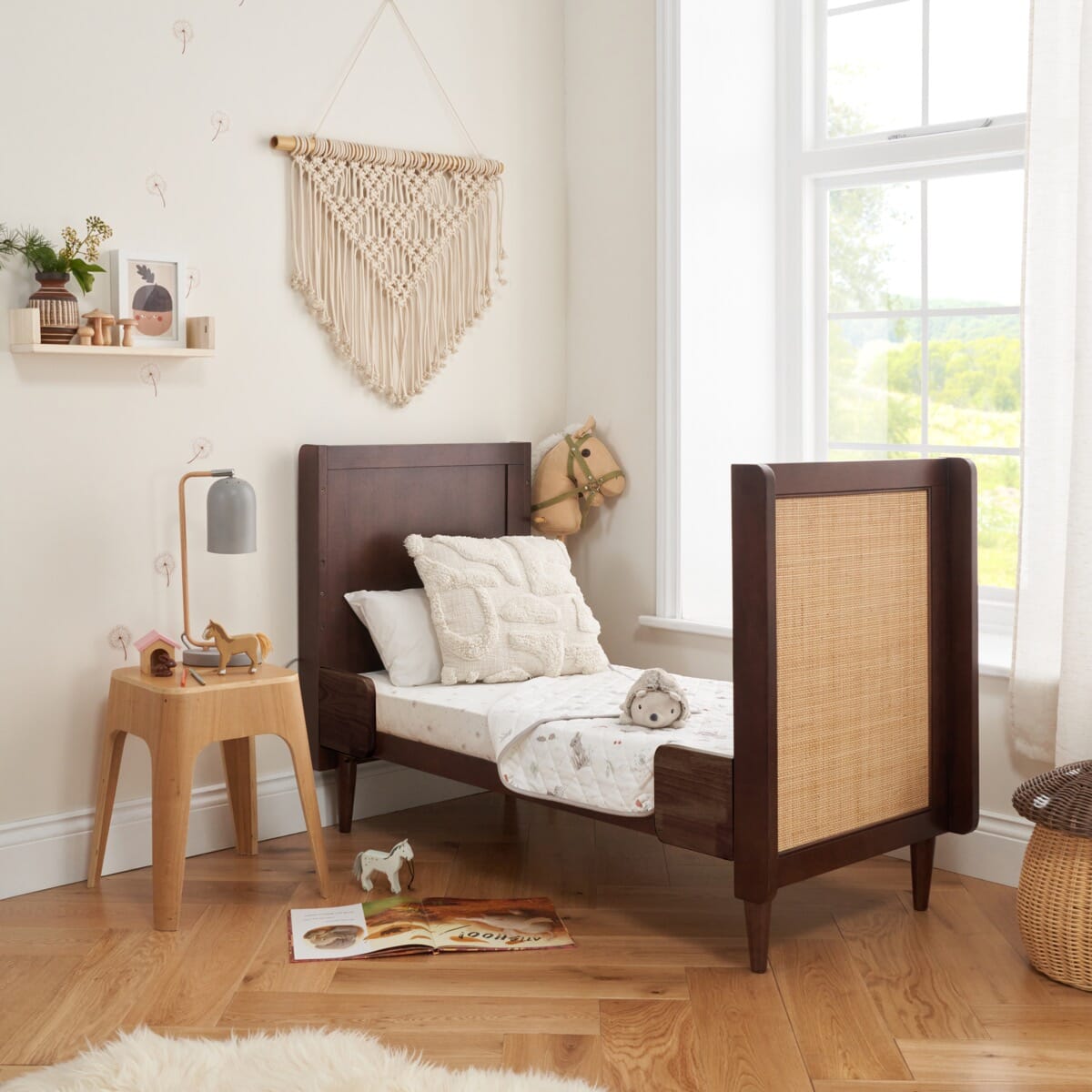 Japandi mini cot bed in warm walnut shown in toddler bed mode, with the side rail removed for an open and independent sleeping solution.