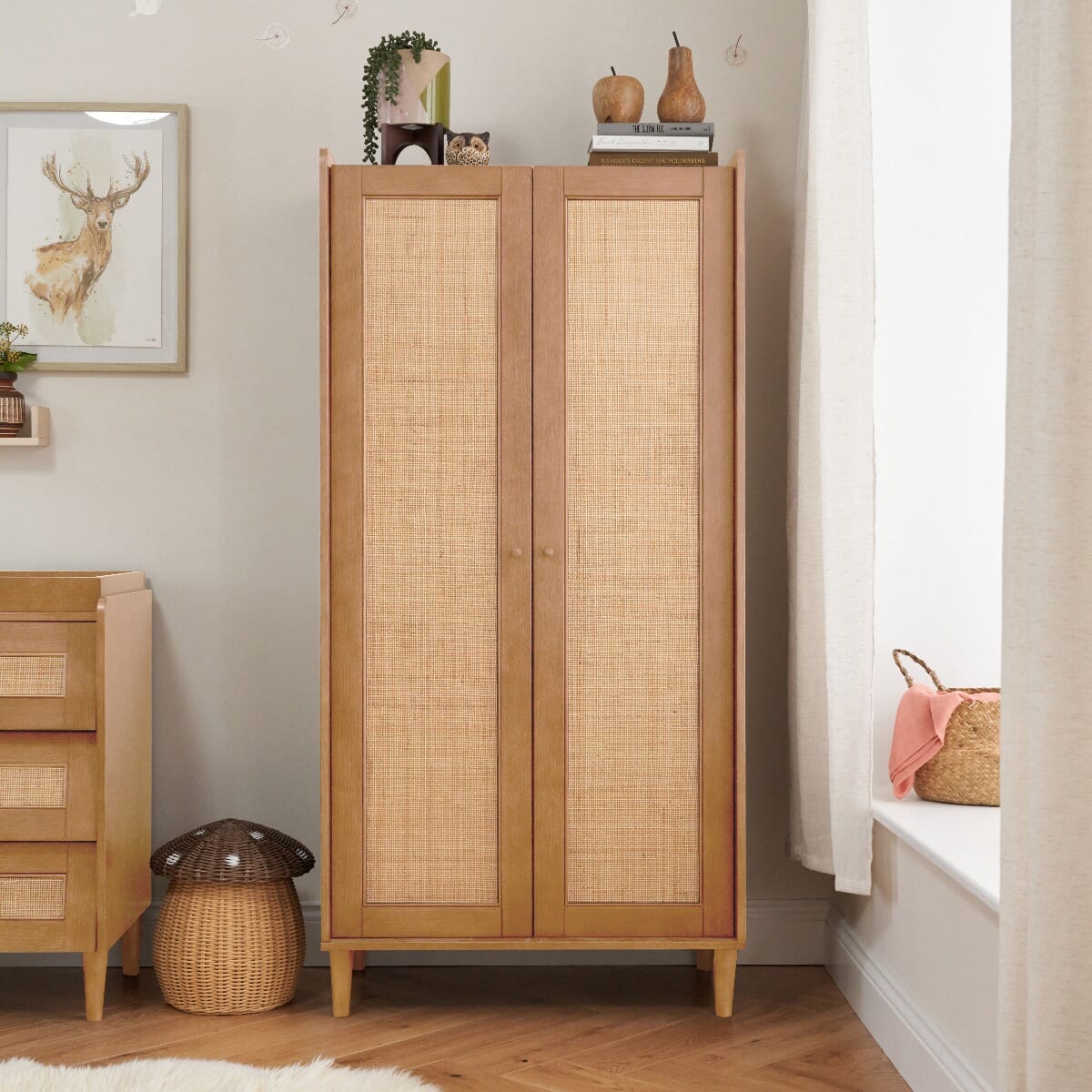Japandi wardrobe in light oak with closed double doors, showcasing a natural rattan panel design and mid-century style legs, ideal for compact and stylish nursery storage.