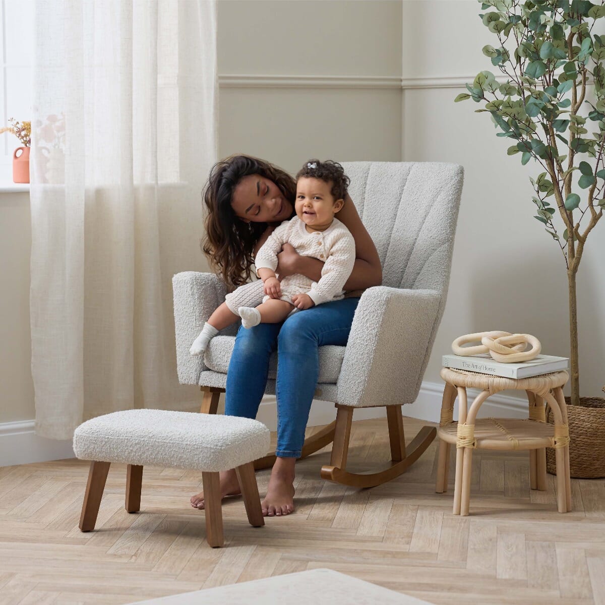 Mum with smiling baby seated in the Jonah Luxe rocking chair and footstool in boucle mushroom, creating a cosy, joyful nursery moment