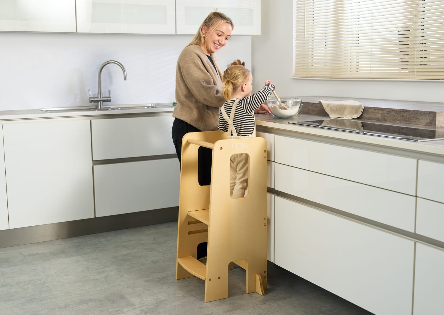 Helping Hands Montessori Toddler Learning Tower in Natural Wood - image of girl on a learning tower helping in kitchen activities