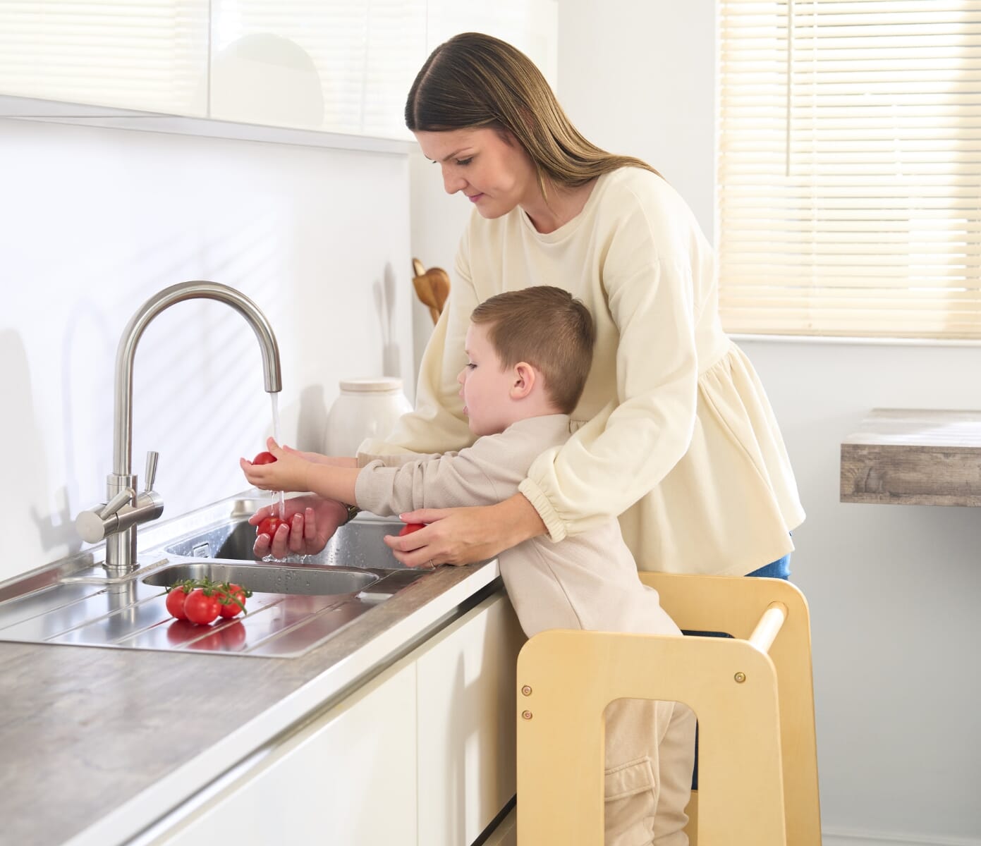 Helping Hands Montessori Toddler Learning Tower in Natural Wood - image of boy on learning tower helping mum to wash vegetables