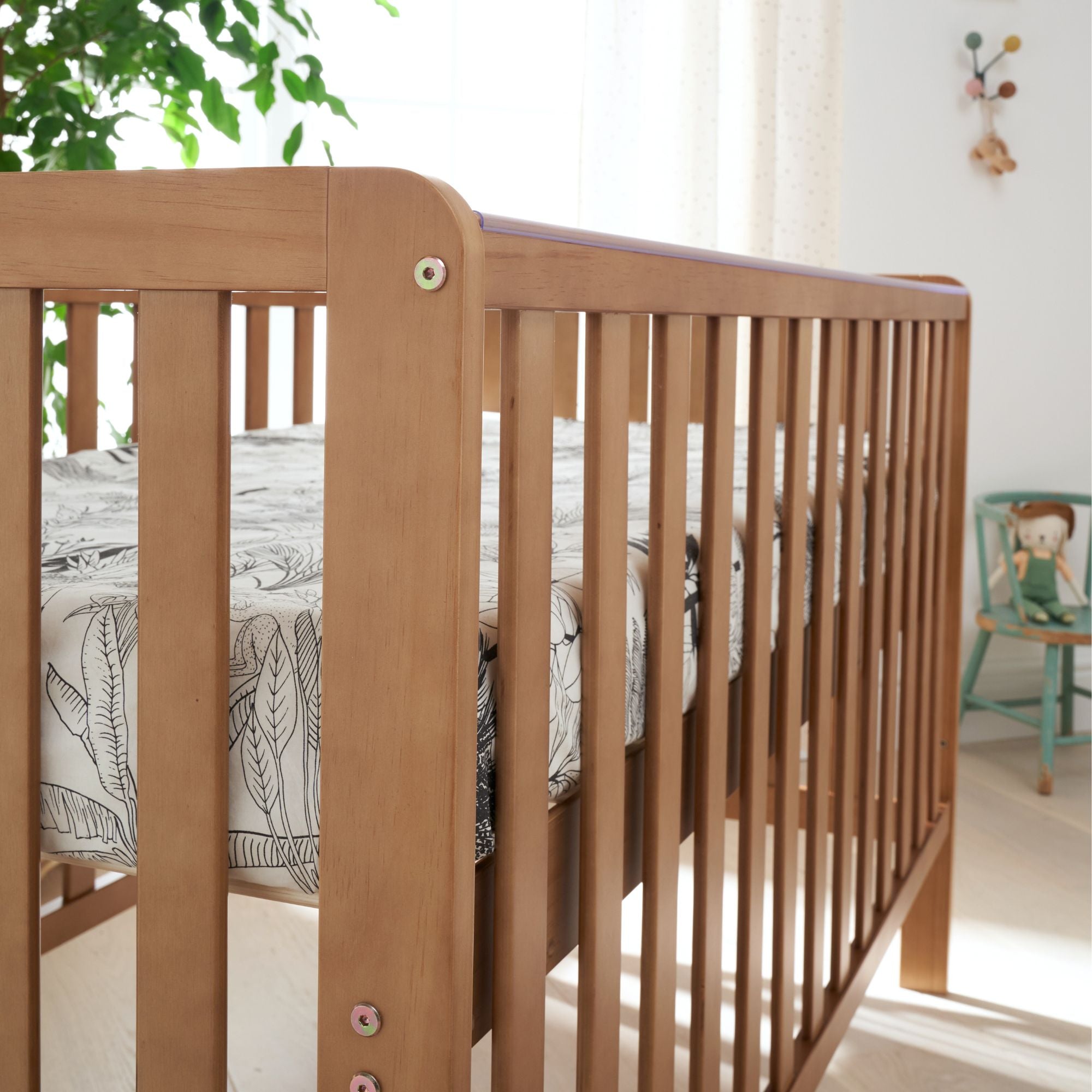 Close-up of the Malmo cot bed in oak showing smooth curved edges and open slats, highlighting quality finish and detailing
