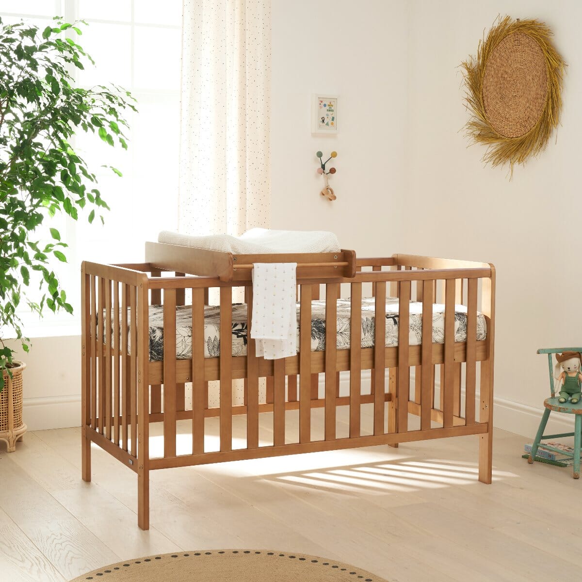 Malmo cot bed in oak with cot top changer in a styled nursery, showcasing practical changing solution and warm wood tone
