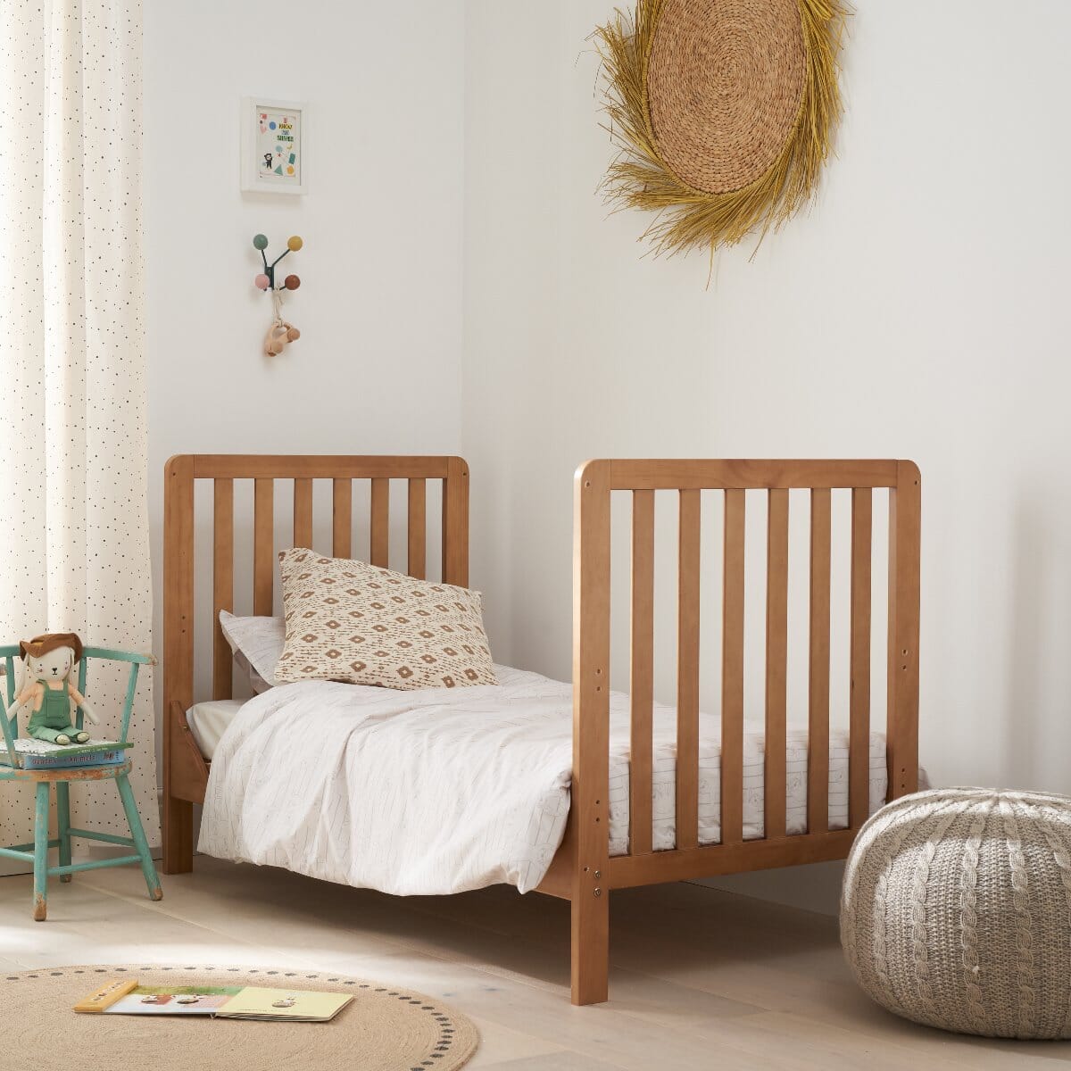 Toddler bed setup of the Malmo cot bed in warm oak, styled in a nursery with soft textiles and wooden toys