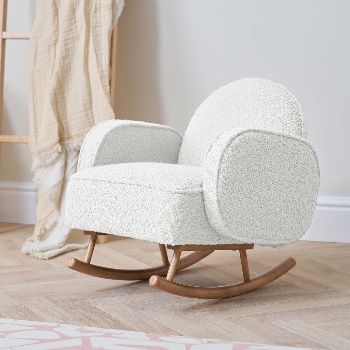 Angled lifestyle view of the Micah Mini Me Rocking Chair in Fresh Cream on timber flooring, featuring ergonomic design and stability for safe rocking.