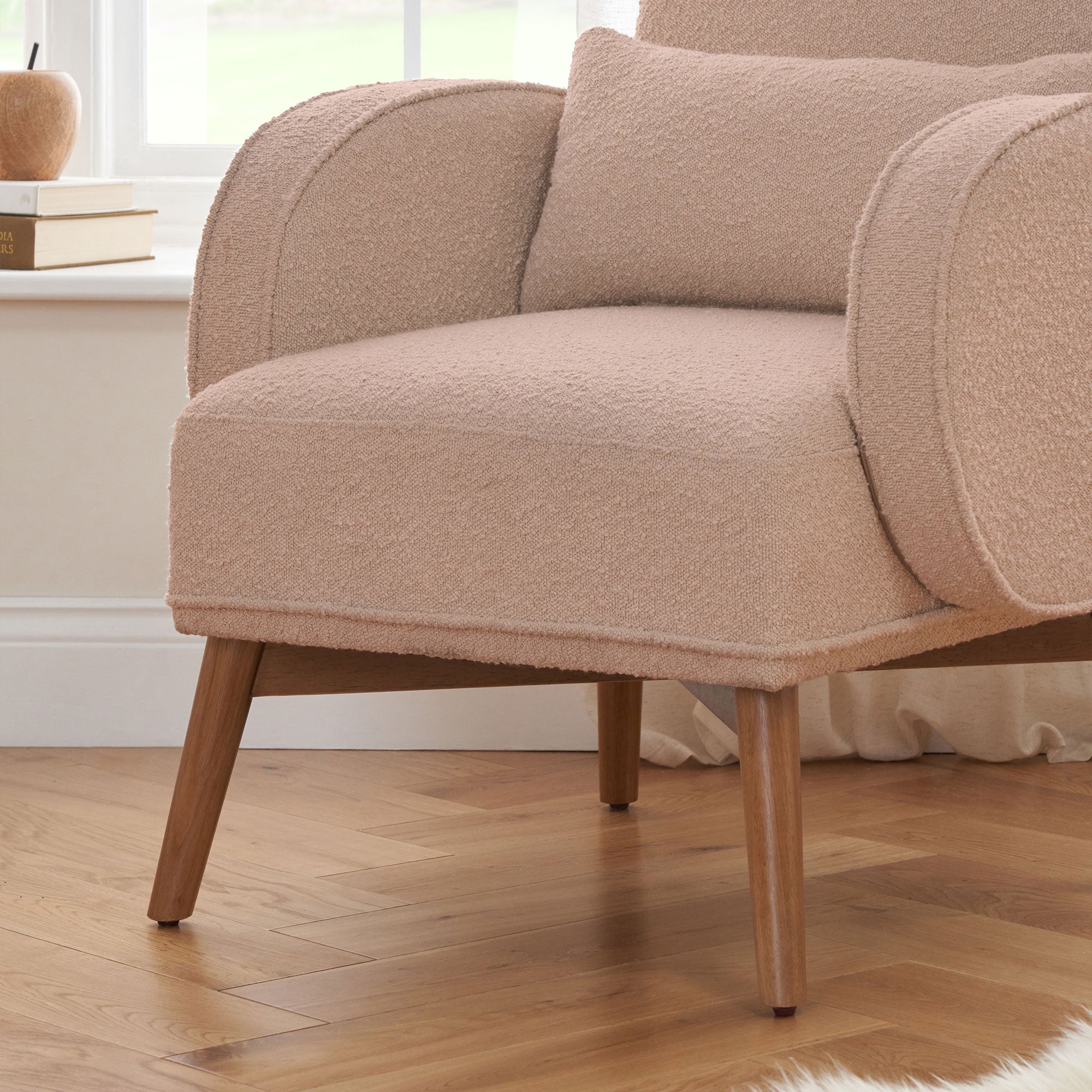 Close-up of Micah Rocking Chair in boucle blush showing cushioned seat with support pillow, curved armrests and wooden legs for comfort and durability.