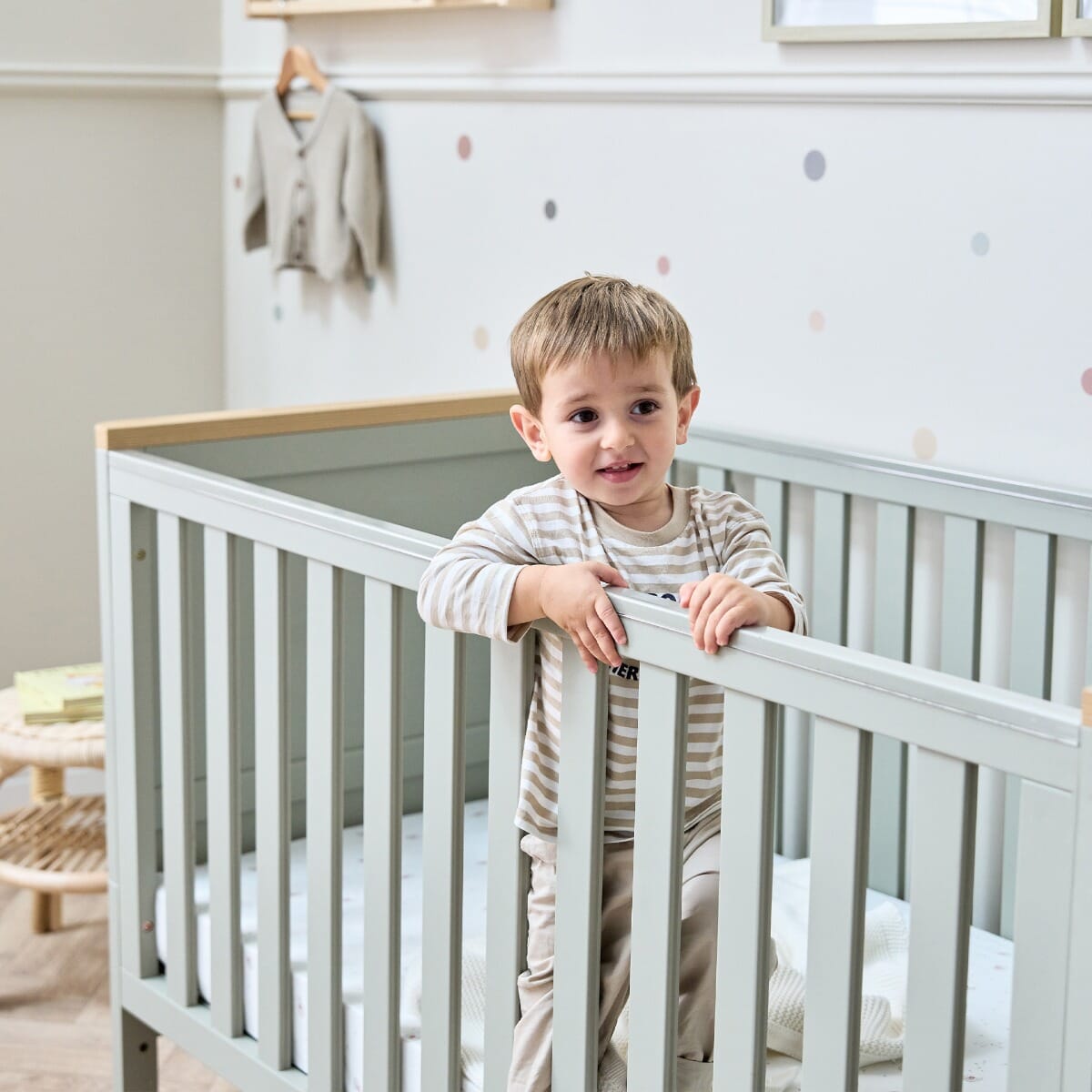 Misha Cot Bed in Sage & Golden Oak - lifestyle image showing details and a kid grabbing the side rail