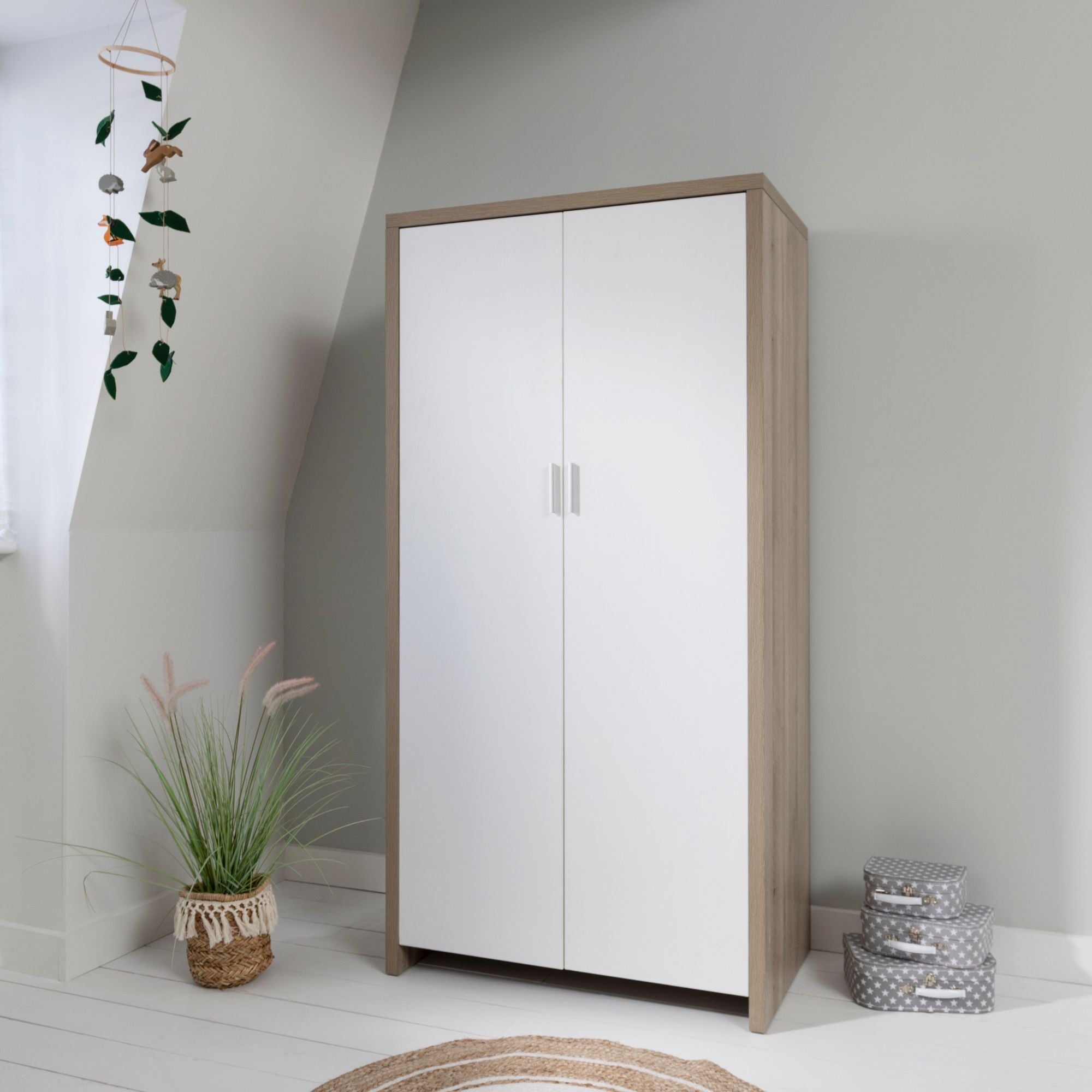 Modena wardrobe in white and oak, closed and placed in a minimalist children's bedroom, offering stylish and practical storage.