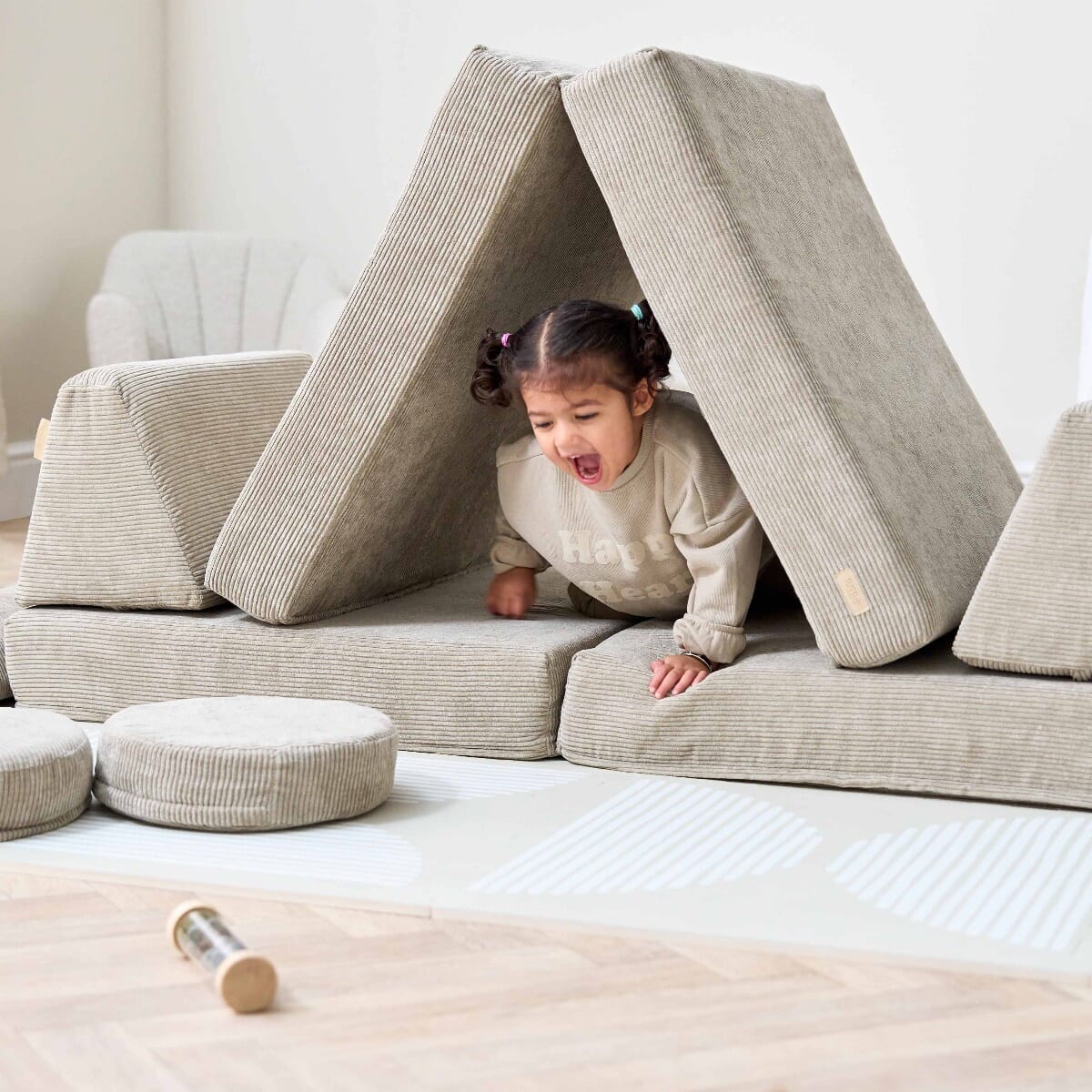 Toddler playing in a den built with the Playrama Montessori Kids Play Sofa in mushroom cord, showing imaginative and creative play use