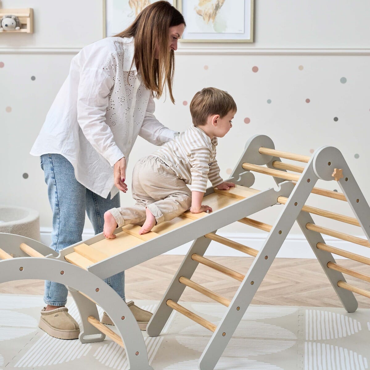 Mother supporting toddler on the Scala Montessori Pikler climbing frame in mushroom finish, encouraging safe and confident play