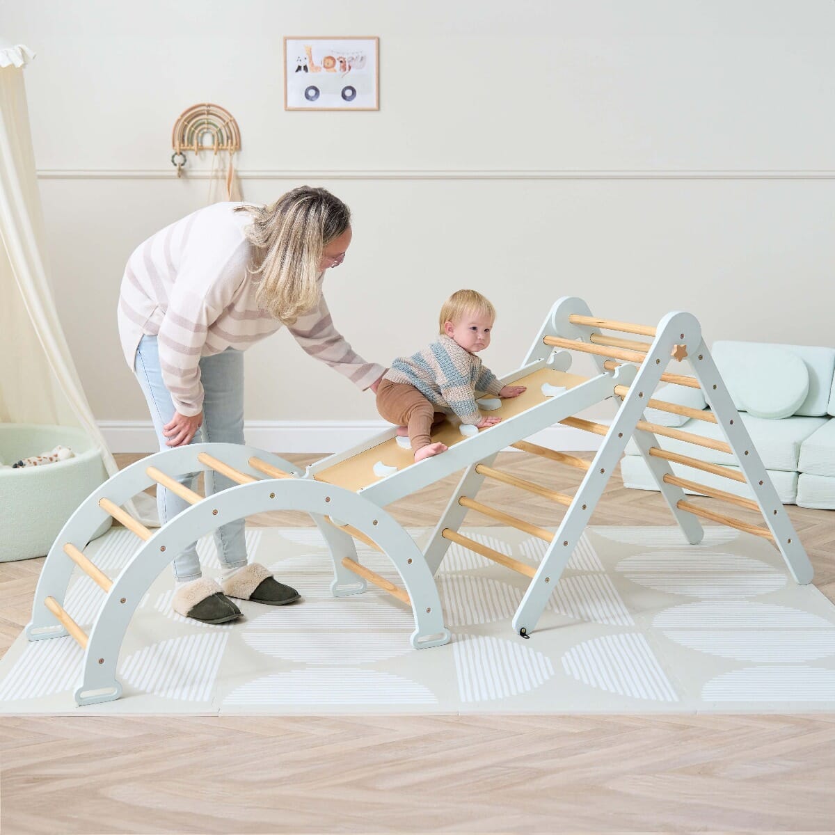 Toddler confidently climbing the Scala Montessori Pikler wall in sea mist, designed to support safe exploration and active movement