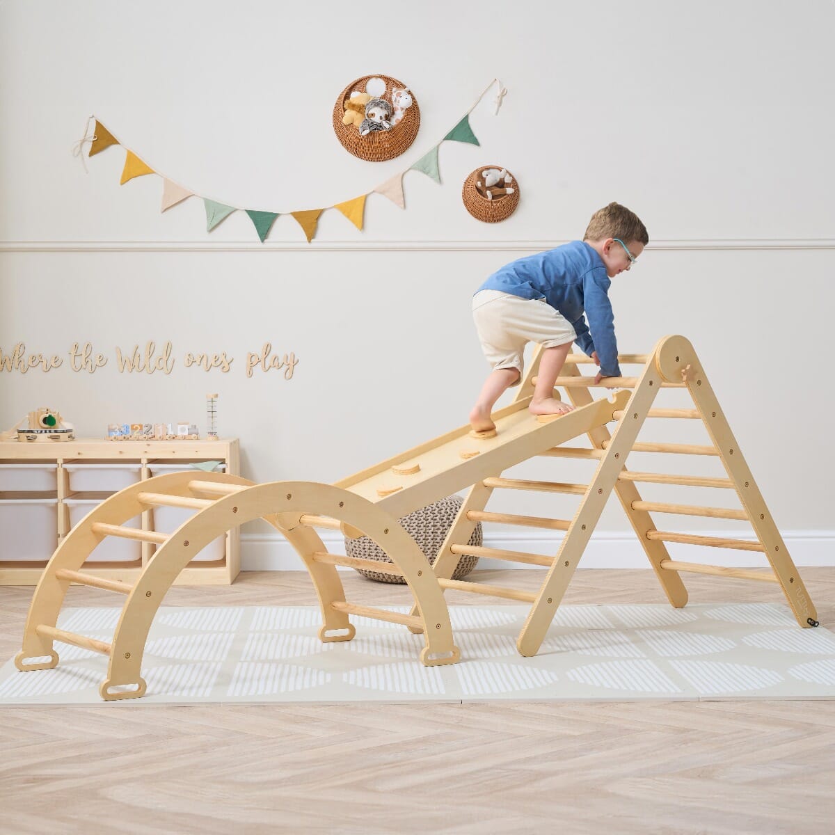 Child climbing the Scala Montessori Pikler Climbing Frame in natural wood finish, building confidence and gross motor skills through play