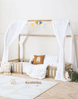 Casa Grande toddler floor bed with curtains styled in a neutral bedroom with colourful bedding and toys.
