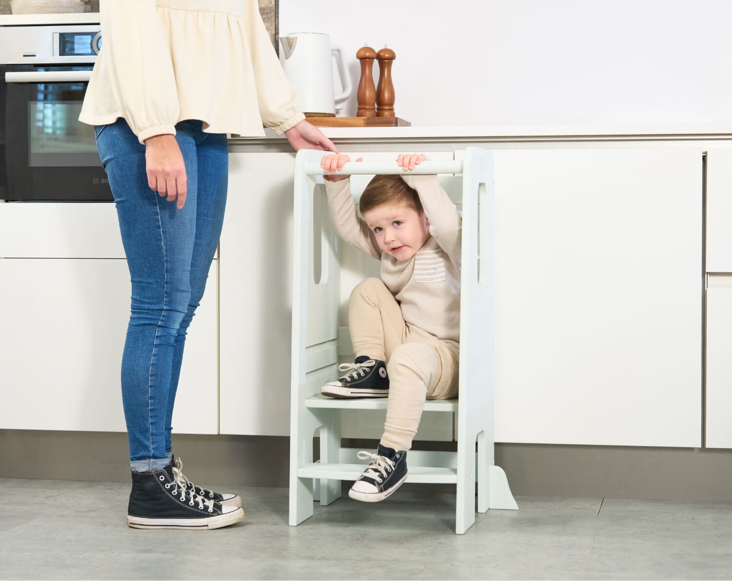toddler sitting on the helping hands montessori toddler learning tower in ocean stone