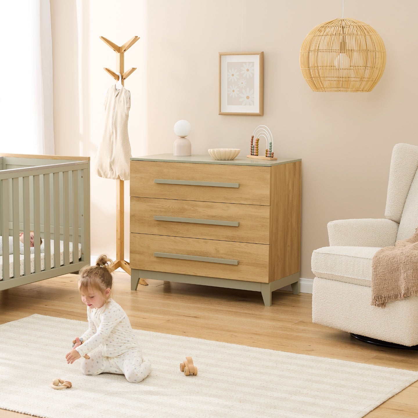 Hallee chest changer in sage and golden oak styled in nursery with cot, rocking chair and toddler playing on rug.