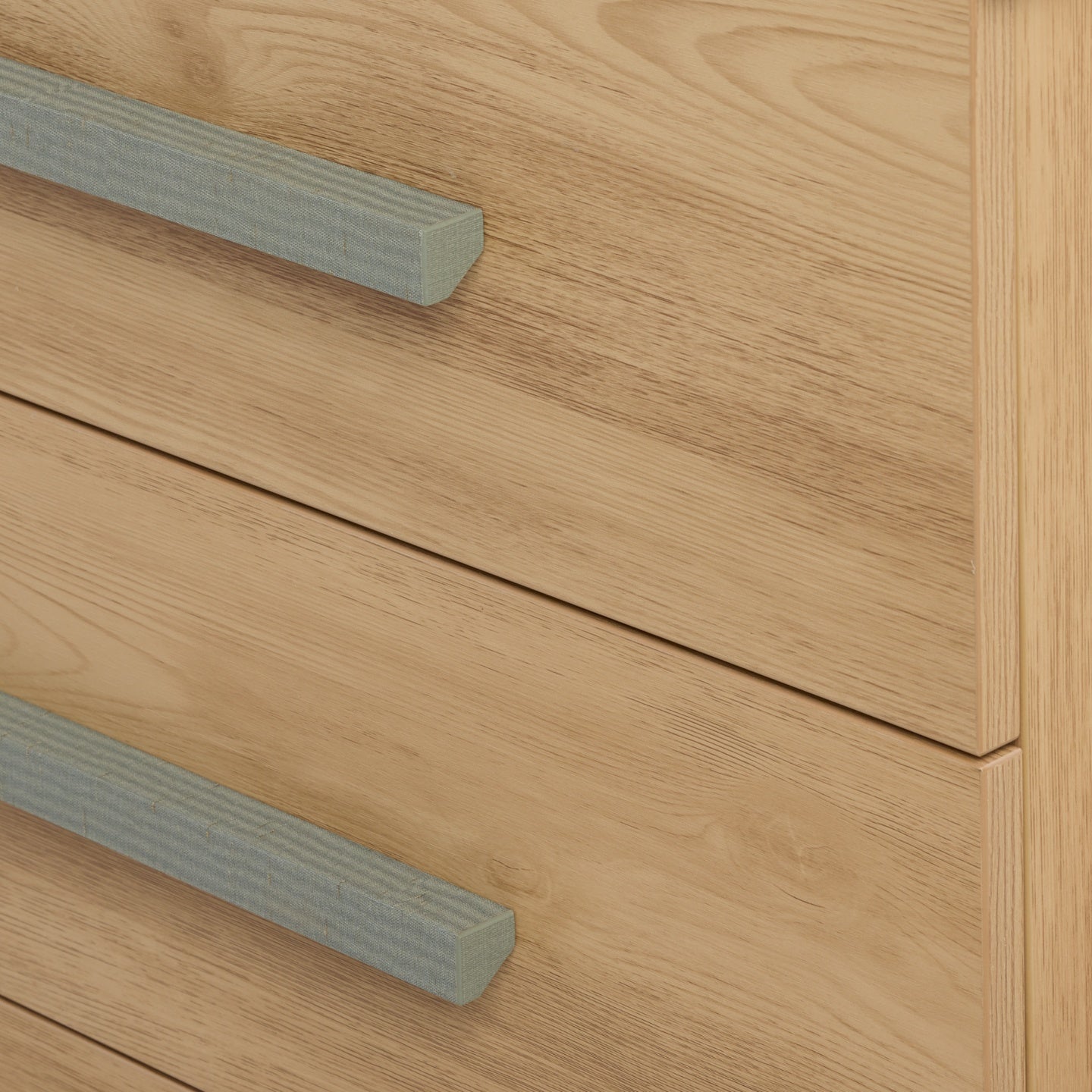Detail of Hallee chest in sage weave and golden oak highlighting wood grain drawers and woven-effect sage handles.