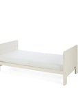 A side view of the Alba cot bed in cashmere converted into a toddler's bed in a white background.