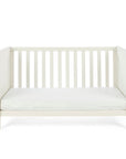 The Alba cot bed in cashmere converted into a toddler's sofa in a white background.