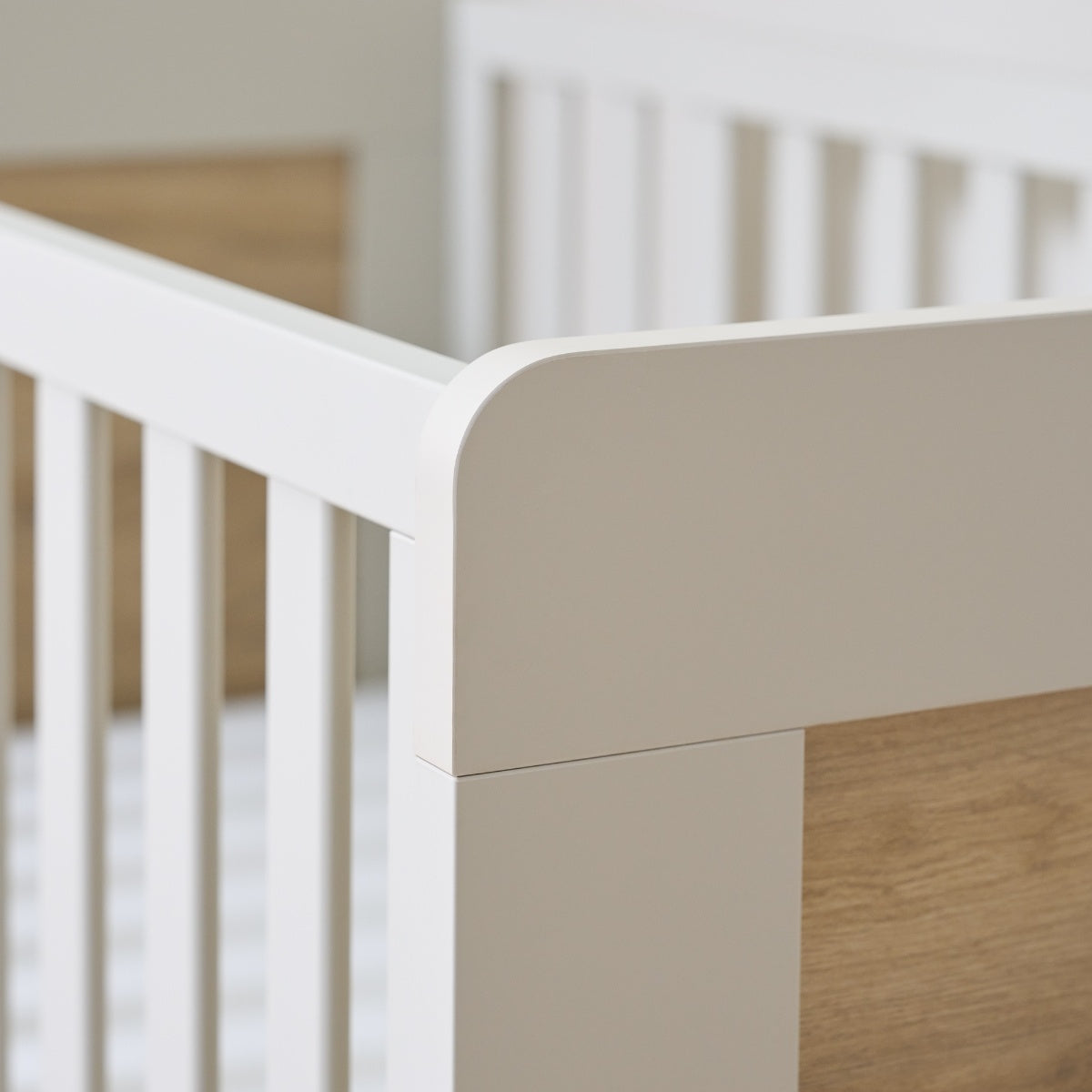 Detail of the Alba cot bed in white sand and distressed oak with soft-touch finish. 