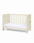 A side view of the mini Alba cot bed in cashmere converted into a toddler's sofa in a white background.