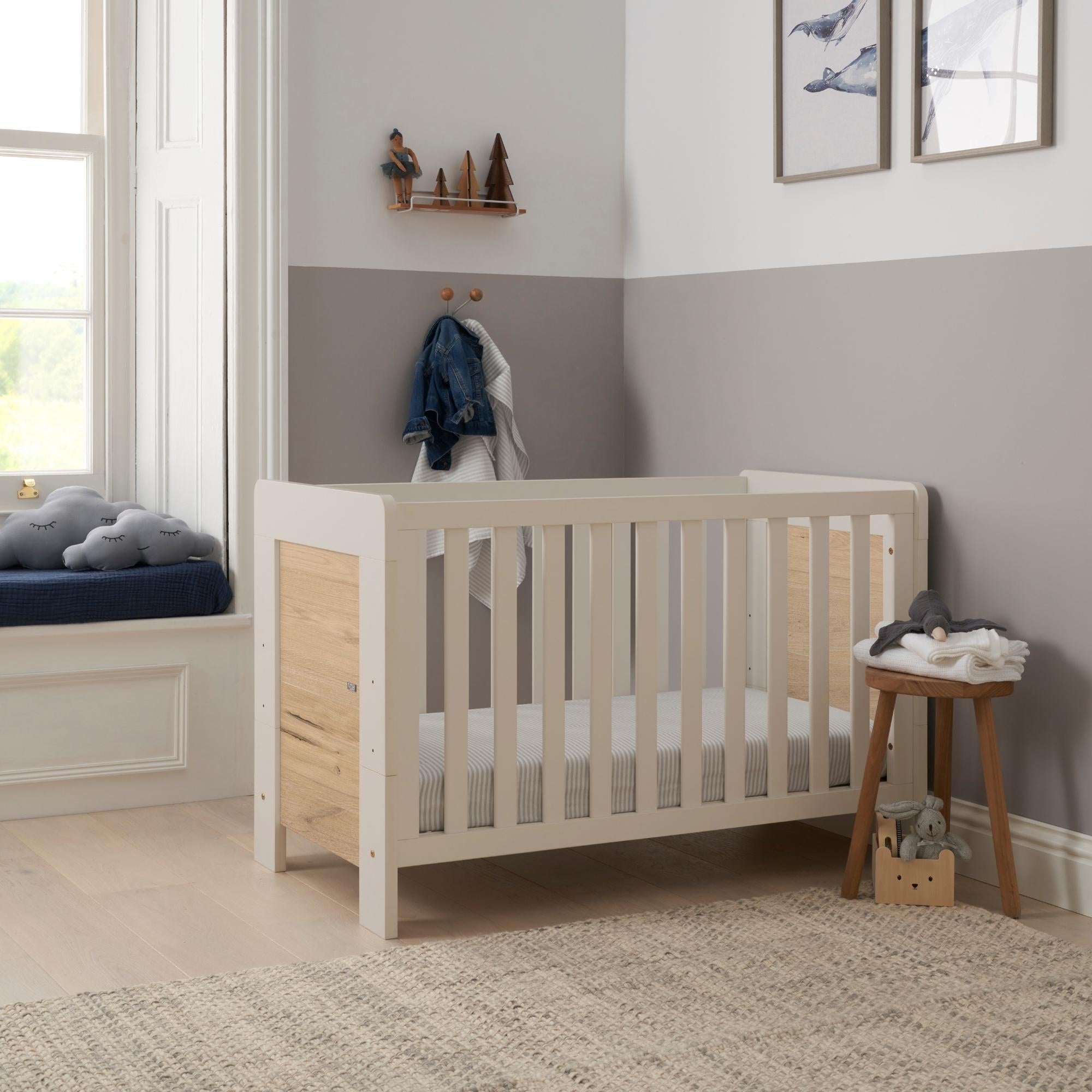 Alba mini cot bed in a modern nursery with a grey wall and a window. 